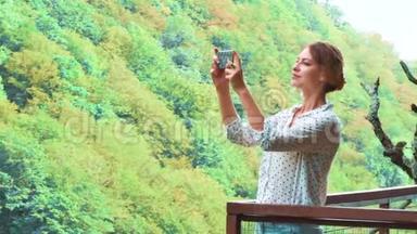 可爱的女孩，金发碧眼的辫子，在她的新手机上制作了高质量的照片，她的新手机在悬崖上的空中桥，奥卡塞斯峡谷。